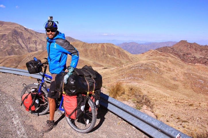 un uomo in piedi su una bicicletta con le borse sul lato della strada